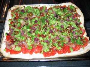 Pizza with tomato slices, broccoli, onions, garlic, olives, and anchovies